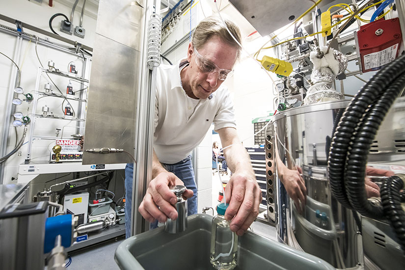 An engineer fills a container of clear liquid in a high-tech laboratory.