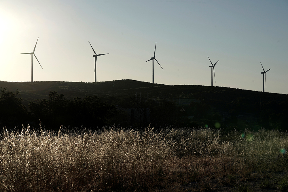 Five windmills stand on a hill above shrubland in Campo, California. 