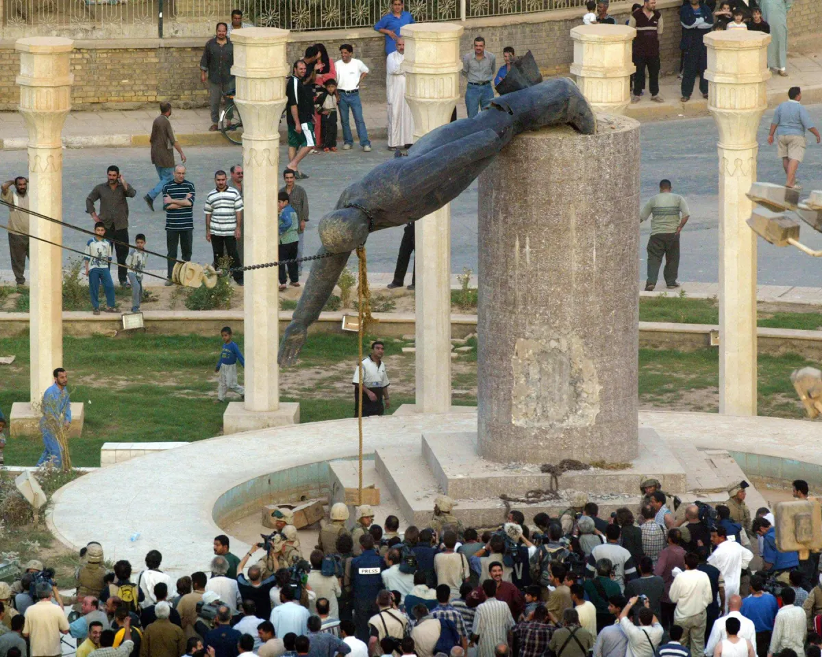 A photo showing Iraqis watching a statue of Iraqi President Saddam Hussein fall in Baghdad's al-Fardous Square on April 9, 2003.