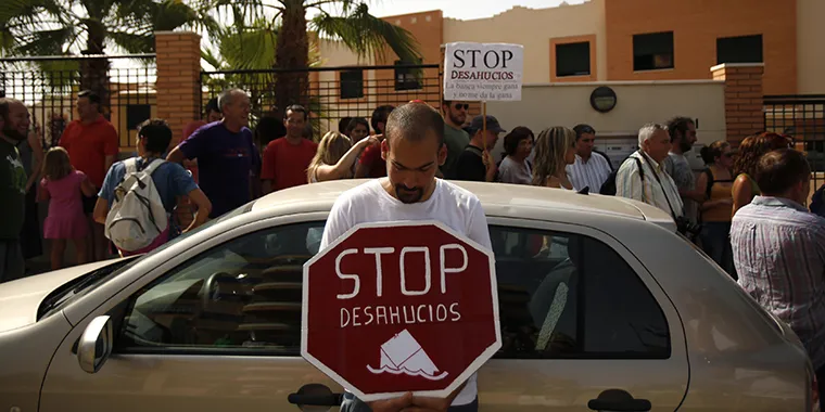 A demonstrator holds a sign that reads “Stop evictions” in Spanish during a protest in Torre del Mar in southern Spain, on June 29, 2011.