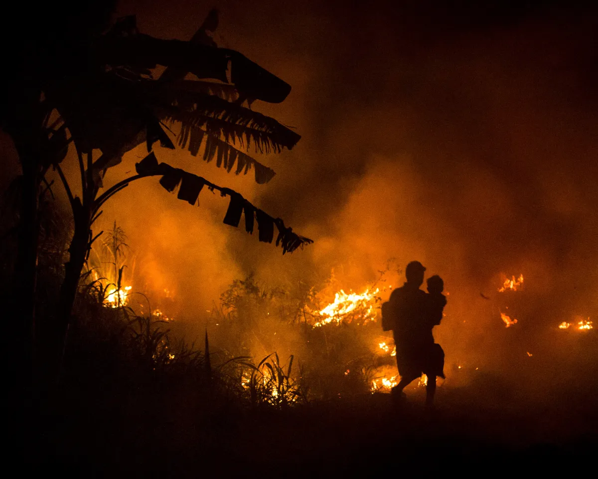 A photo showing a man carrying his son home through haze from a fire set to clear new land for the production of pulp, paper and palm oil in South Sumatra, Indonesia, on October 2, 2015.