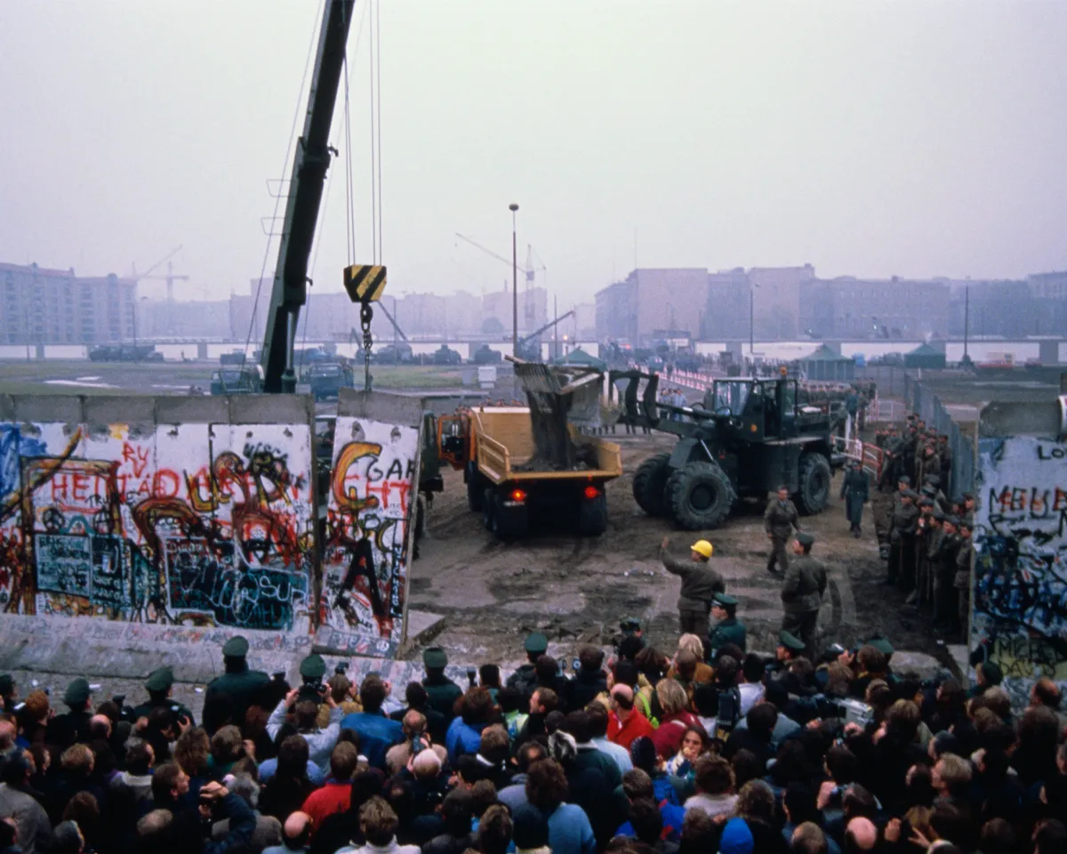 A crowd watching as workmen deconstruct the Berlin Wall in Germany in late 1989.