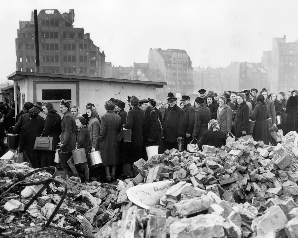 A photo of citizens of Hamburg, Germany lining up among the city's ruins for soup rations on March 26, 1946.