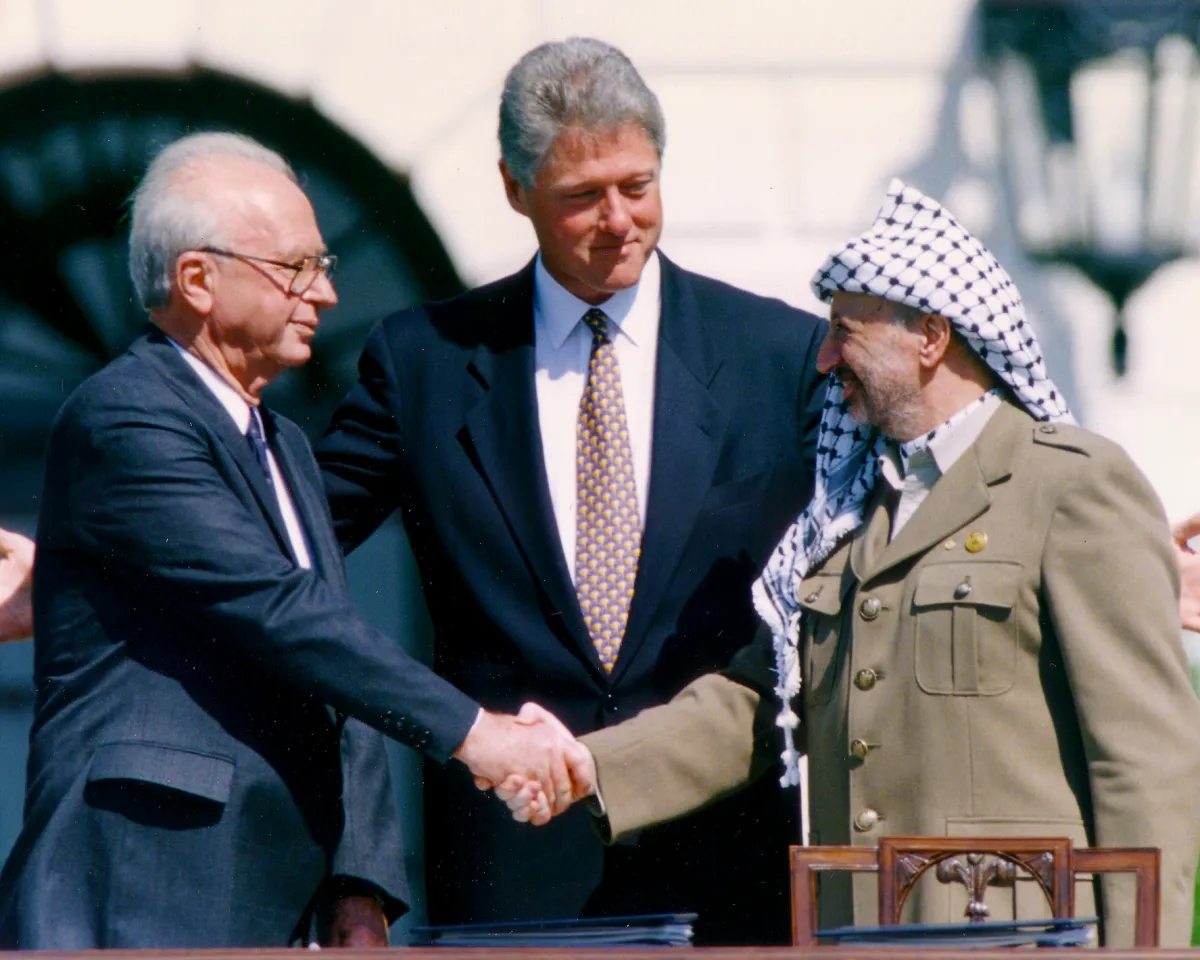 A photo showing Palestine Liberation Organization Chairman Yasser Arafat (R) shaking hands with Israeli Prime Minister Yitzhak Rabin (L), as U.S. President Bill Clinton stands between them, after signing the Oslo Accord on September 13, 1993.