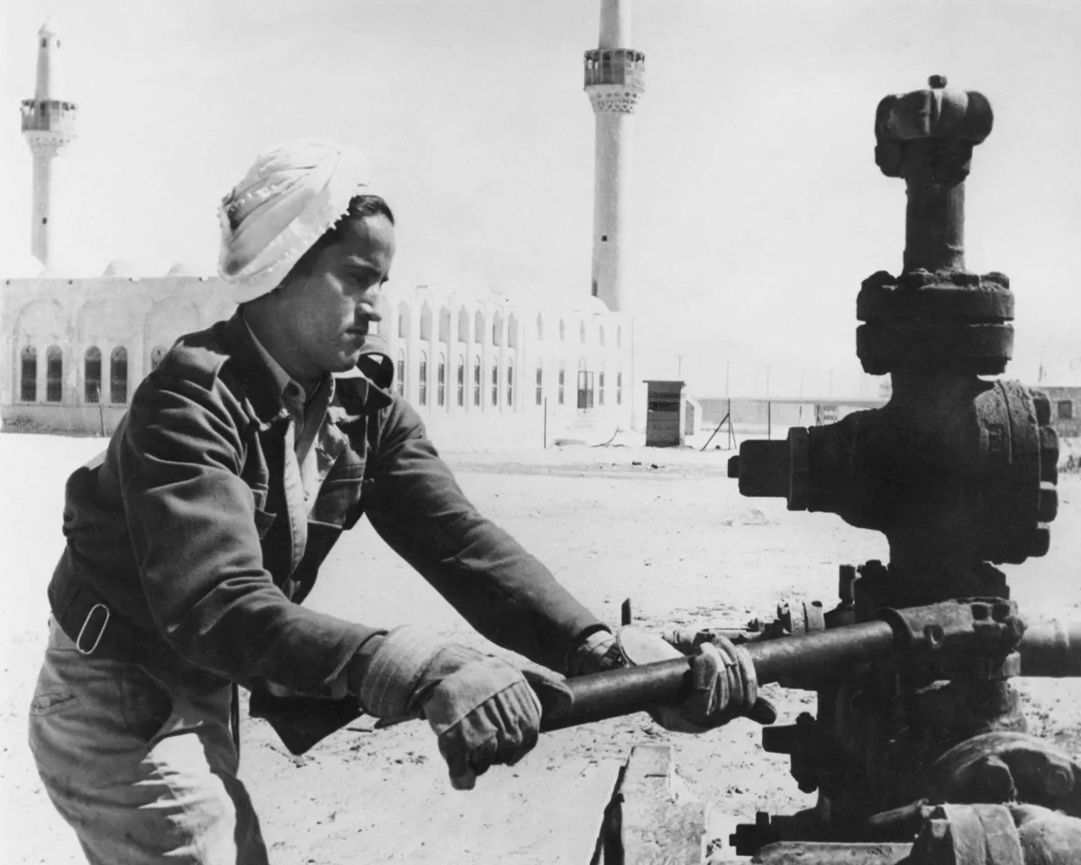 A photo showing an oil worker adjusting a valve outside a mosque in Saudi Arabia in 1960.