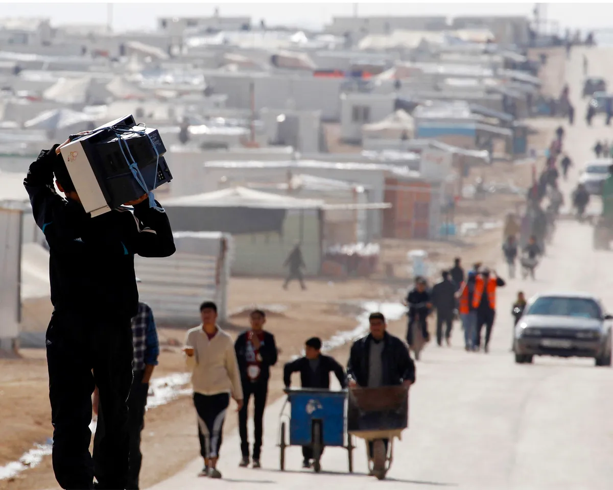 A photo showing a Syrian refugee carrying a television as he walks at al-Zaatri refugee camp in Mafraq, Jordan, on December 31, 2013.
