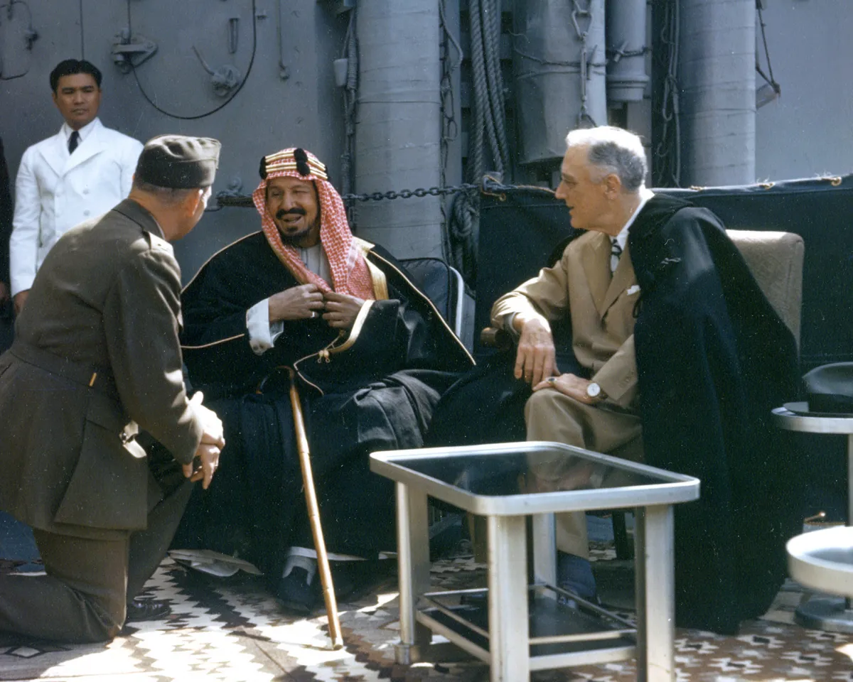 A photo showing, aboard the U.S.S. Quincy in Egypt's Great Bitter Lake, King Abdul Aziz Ibn Saud of Saudi Arabia speaking to an American Marine Corps translator as U.S. President Franklin D. Roosevelt listens on February 14, 1945.
