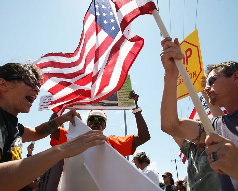 A photo showing a protester who opposes the arrival of buses bringing undocumented migrants to the Murrieta Border Patrol Station and a counter-demonstrator facing off in Murrieta, California, on July 4, 2014.