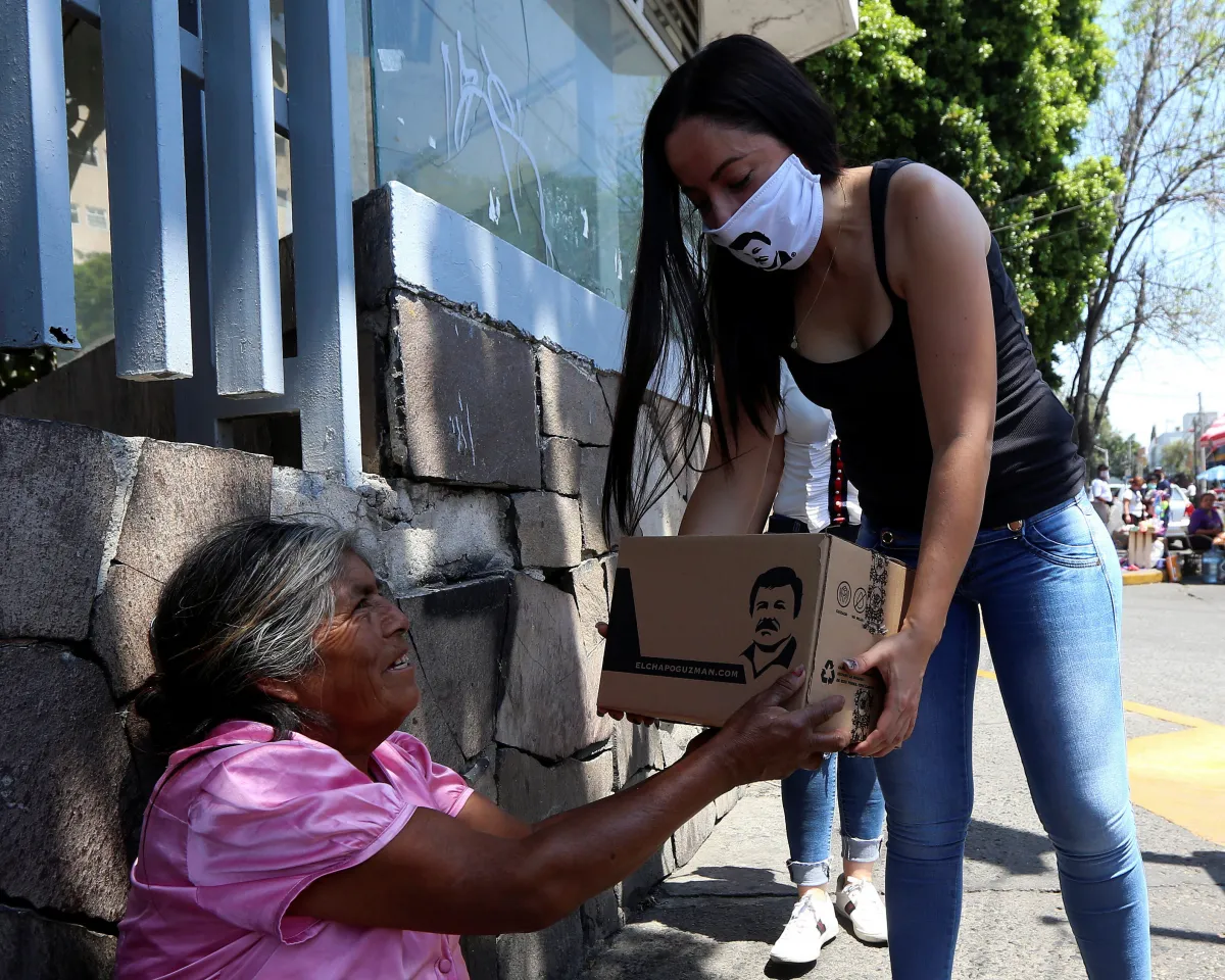 A photo showing an employee of a clothing brand owned by a daughter of the convicted drug kingpin Joaquin "El Chapo" Guzman, hands out a box with food, face masks, and hand sanitizers to an elderly woman in Guadalajara, Mexico, on April 16, 2020.