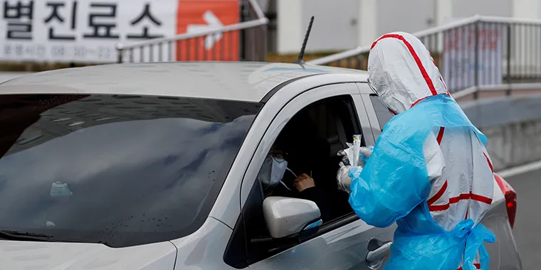 A medical staff member in protective gear prepares to take samples from a visitor at a "drive-thru" testing center for the novel coronavirus disease of COVID-19 in Yeungnam University Medical Center in Daegu, South Korea, on March 3, 2020.
