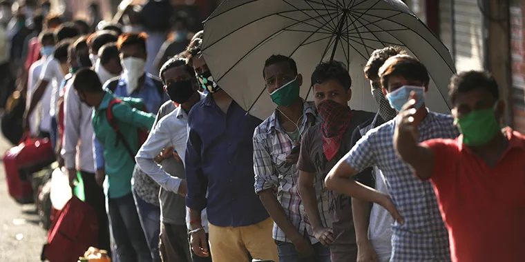 Migrants wearing protective face masks stand in a queue as they wait for transportation to a railway station, during an extended lockdown to slow the spread of the coronavirus disease (COVID-19), in Mumbai, India, on May 22, 2020.