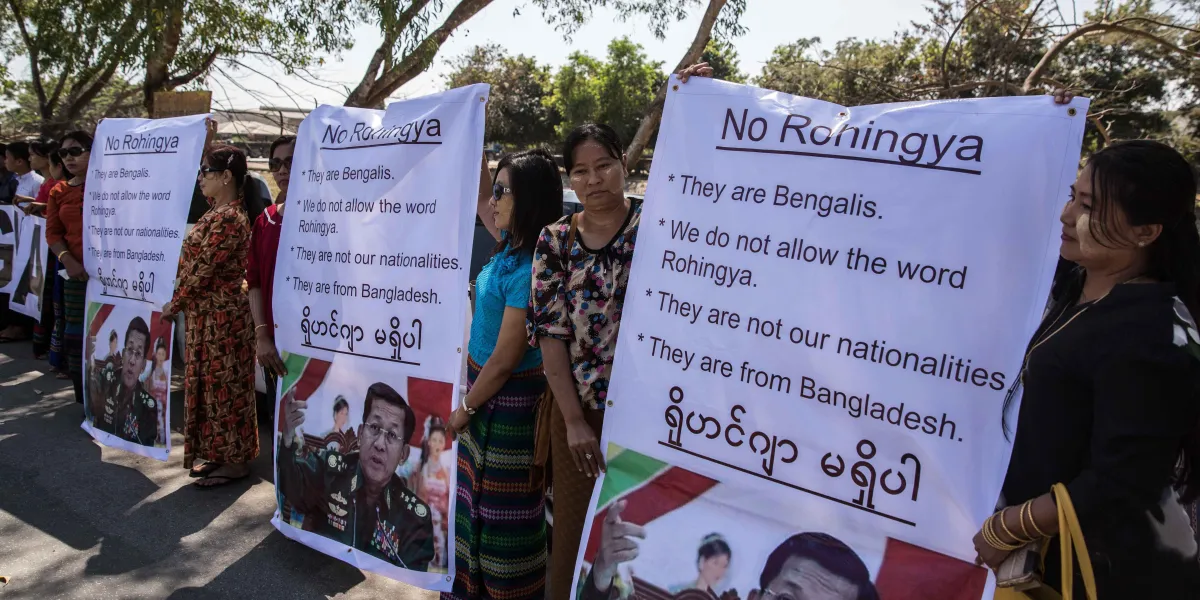 Protesters hold signs objecting to the word "Rohingya" as an aid ship headed for Rohingya refugee camps docks in Myanmar in 2017. 