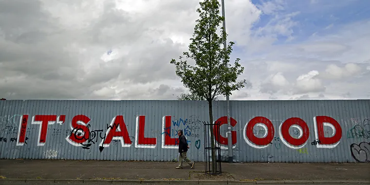 A man walks past graffiti on a section of a peace wall near the Shankill Road in West Belfast on June 14, 2013.