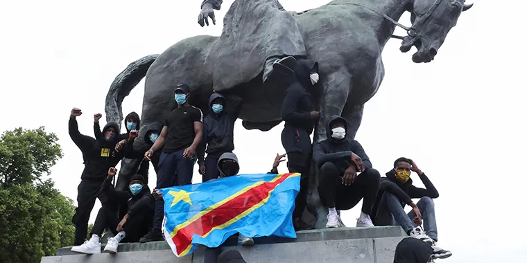 Demonstrators stand on the statue of Leopold II as one of them holds a national flag of the Democratic Republic of Congo during a protest in central Brussels, Belgium, on June 7, 2020.