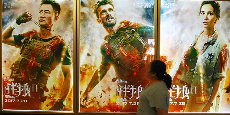 A Chinese filmgoer walks past posters of the Chinese action movie "Wolf Warrior II" at a movie theater in Yichang in central China's Hubei province on August 20, 2017.