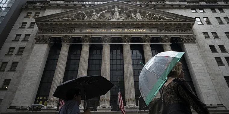 People walk past the New York Stock Exchange on a rainy day in the Financial District on October 11, 2018 in New York City.