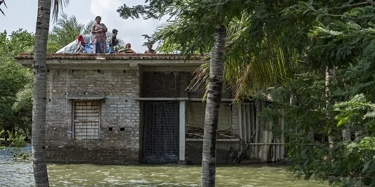 A family takes shelter on the rooftop as river embankments have broken and several villages flooded on May 28, 2021 in South 24 Parganas, West Bengal, India.
