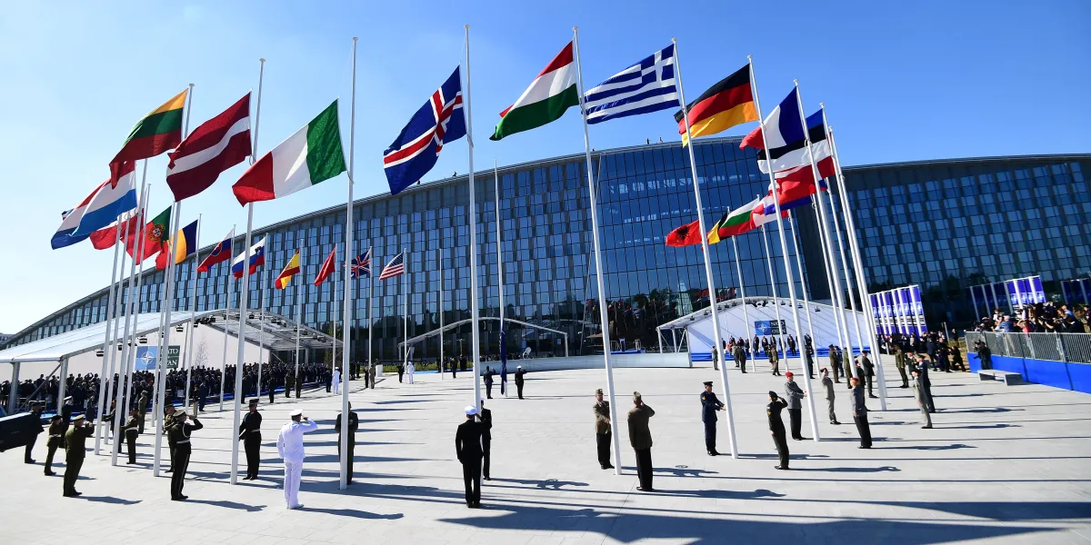 Officials and military personnel stand beneath flags as they attend the NATO (North Atlantic Treaty Organization) summit ceremony at the NATO headquarters, in Brussels, on May 25, 2017.