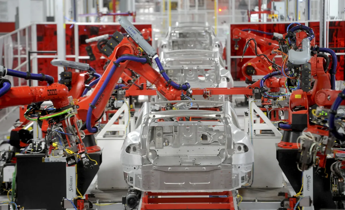 Robotic arm assembles car in factory.