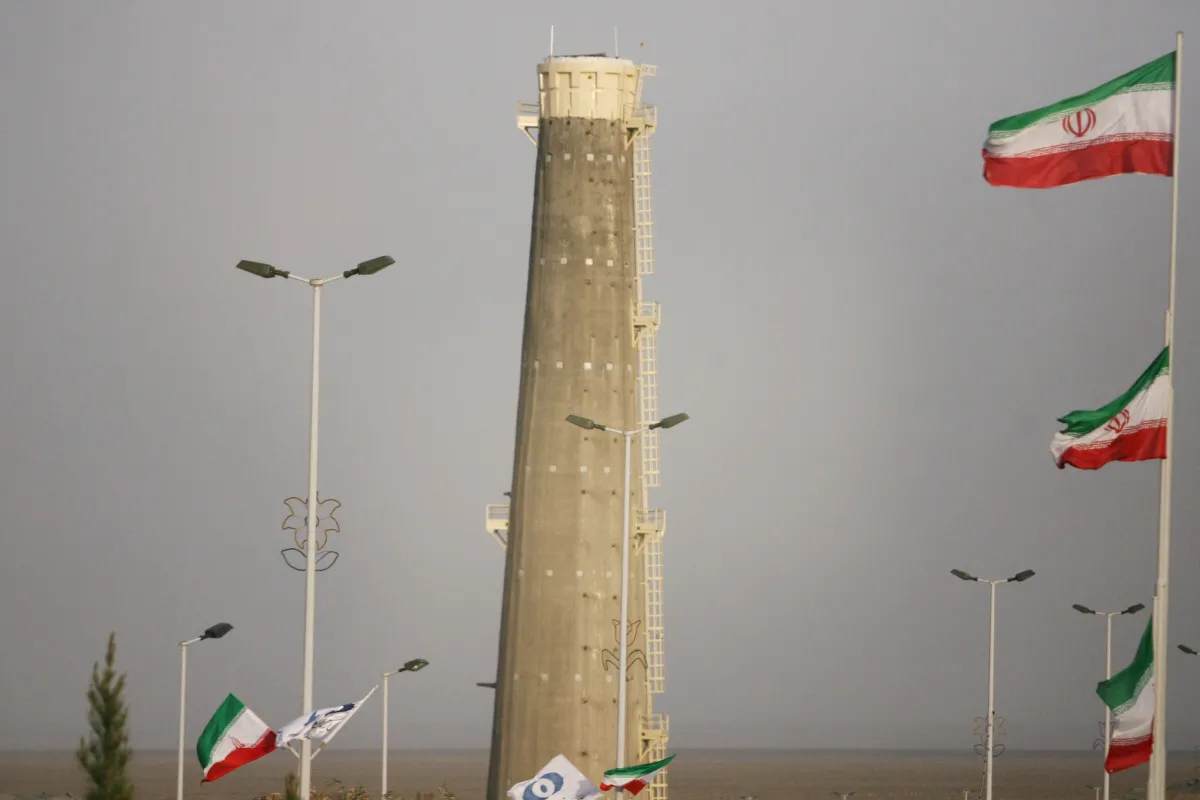 Large concrete tower rises up behind a row of parking lot lights and Iranian flags.