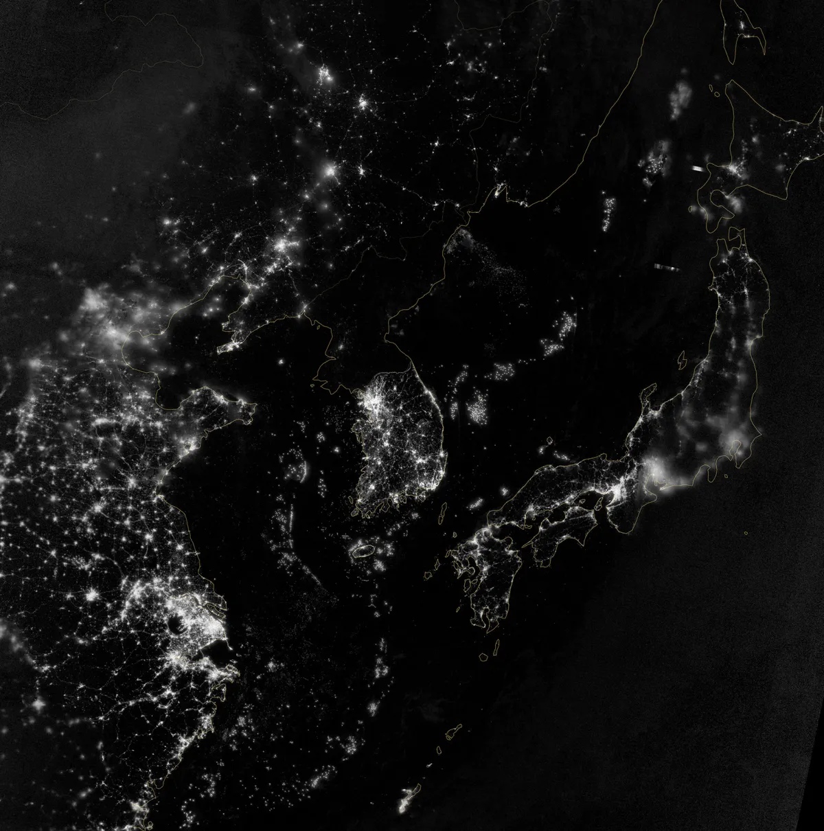 Photo from satellite at night showing East Asia. China, Japan, and South Korean cities appear as bright lights, but North Korea is mostly in darkness.
