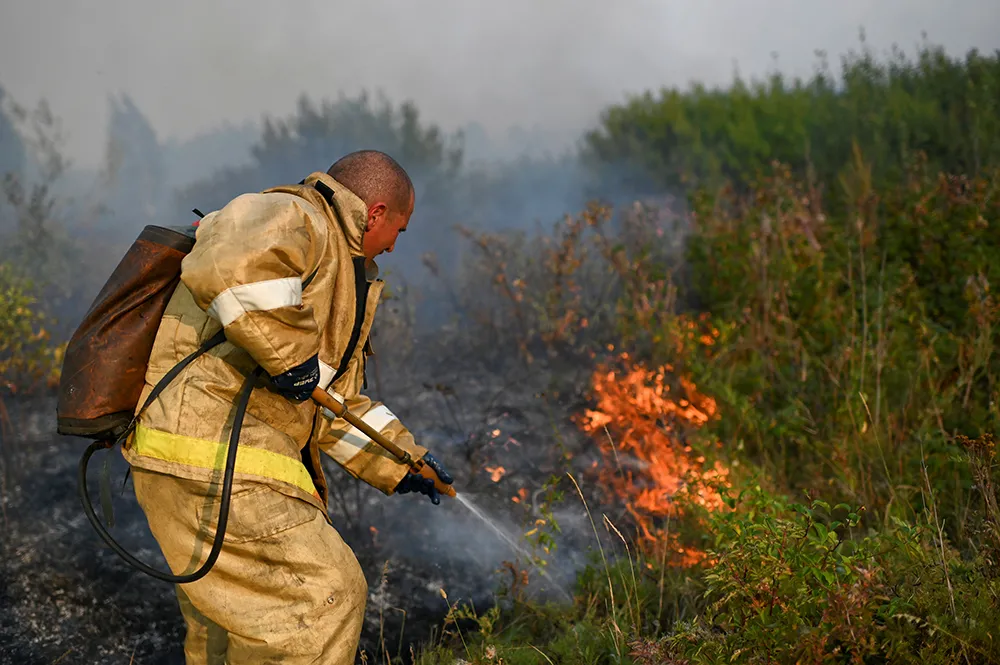 Russian firefighter sprays water on burning bush