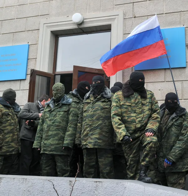 Unidentified masked individuals hold a Russian flag as they block the Trade Union building in Simferopol, the administrative center of Crimea, on March 1, 2014.