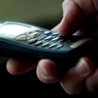 A cell phone user types a text message on his handset in London on January 25, 2002.