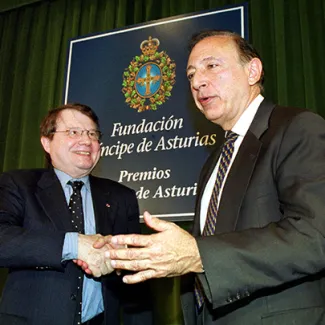 From left, scientists Luc Montagnier and Robert Gallo shake hands after a news conference in Oviedo, Spain, on October 26, 2000. Montagnier and Gallo are credited for identifying the HIV virus.