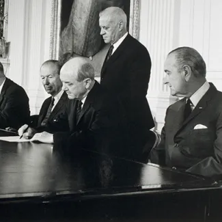 U.S. President Lyndon B. Johnson looks on as Secretary of State Dean Rusk signs the Treaty on the Nonproliferation of Nuclear Weapons on July 1, 1968.