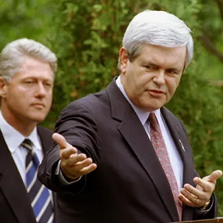 House Speaker Newt Gingrich makes opening remarks as President Bill Clinton looks on at a question and answer meeting between the two leaders in Claremont, New Hampshire, on June 11, 1995.