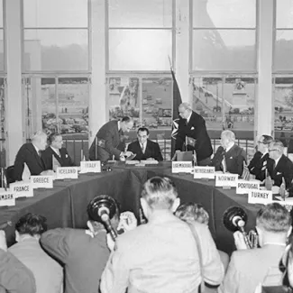 Foreign ministers from NATO counties look on as Pierre Mendes-France, the French foreign minister, signs the treaties making West Germany a part of NATO on October 22, 1954.