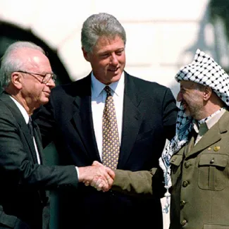 Palestine Liberation Organization Chairman Yasser Arafat (R) shake hands with Israeli Prime Minister Yitzhak Rabin (L), as U.S. President Bill Clinton stands between them, after signing the Oslo Accord, in Washington, D.C., on September 13, 1993.