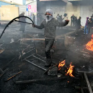 A Palestinian protests the Israeli offensive in Gaza by throwing stones at Israeli border police officers at a refugee camp in the West Bank near Jerusalem on December 29, 2008.