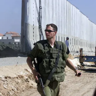 An Israeli soldier guards the new fence built by Israel at the outskirts of the Palestinian West Bank city of Qalkilya, on June 23, 2002. 
