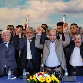 Senior Fatah official Azzam Al-Ahmed, head of the Hamas government Ismail Haniyeh, and senior Hamas leader Moussa Abu Marzouq raise their hands after announcing a reconciliation agreement in Gaza City on April 23, 2014.